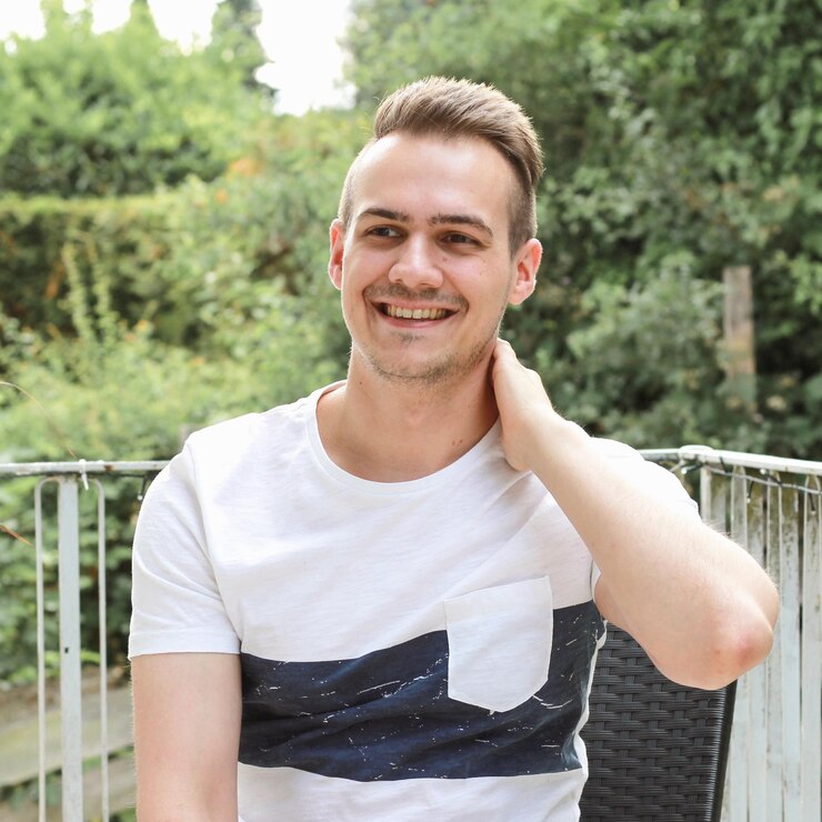 portrait-smiling-young-man-standing-against-railing